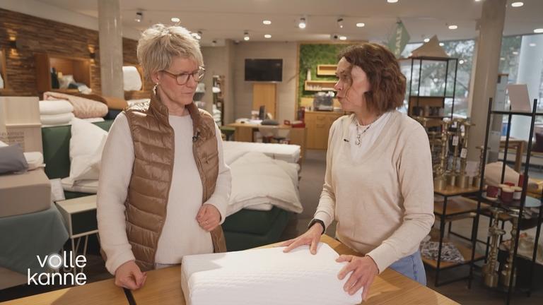 Verkaufsleiterin Katrin Marsch erklärt einer Frau, worauf es bei der Pflege eines Kissens ankommt.