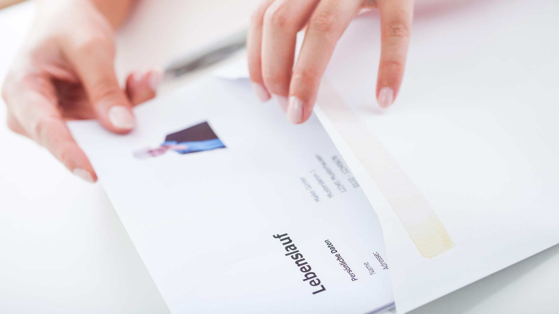 Eine Frau steckt eine Bewerbung in einen Umschlag