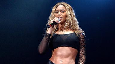 Die Sängerin Beyoncé steht auf der Bühne und hält ein Mikrofon in der rechten Hand.
