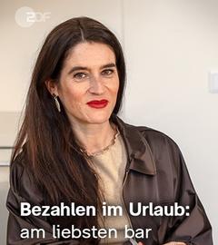 Sina Mainitz steht an einem Tisch. Schrift "Bezahlen im Urlaub: am liebsten bar"