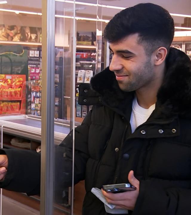 Mann bezahlt im Supermarkt mit einer Bezahlkarte