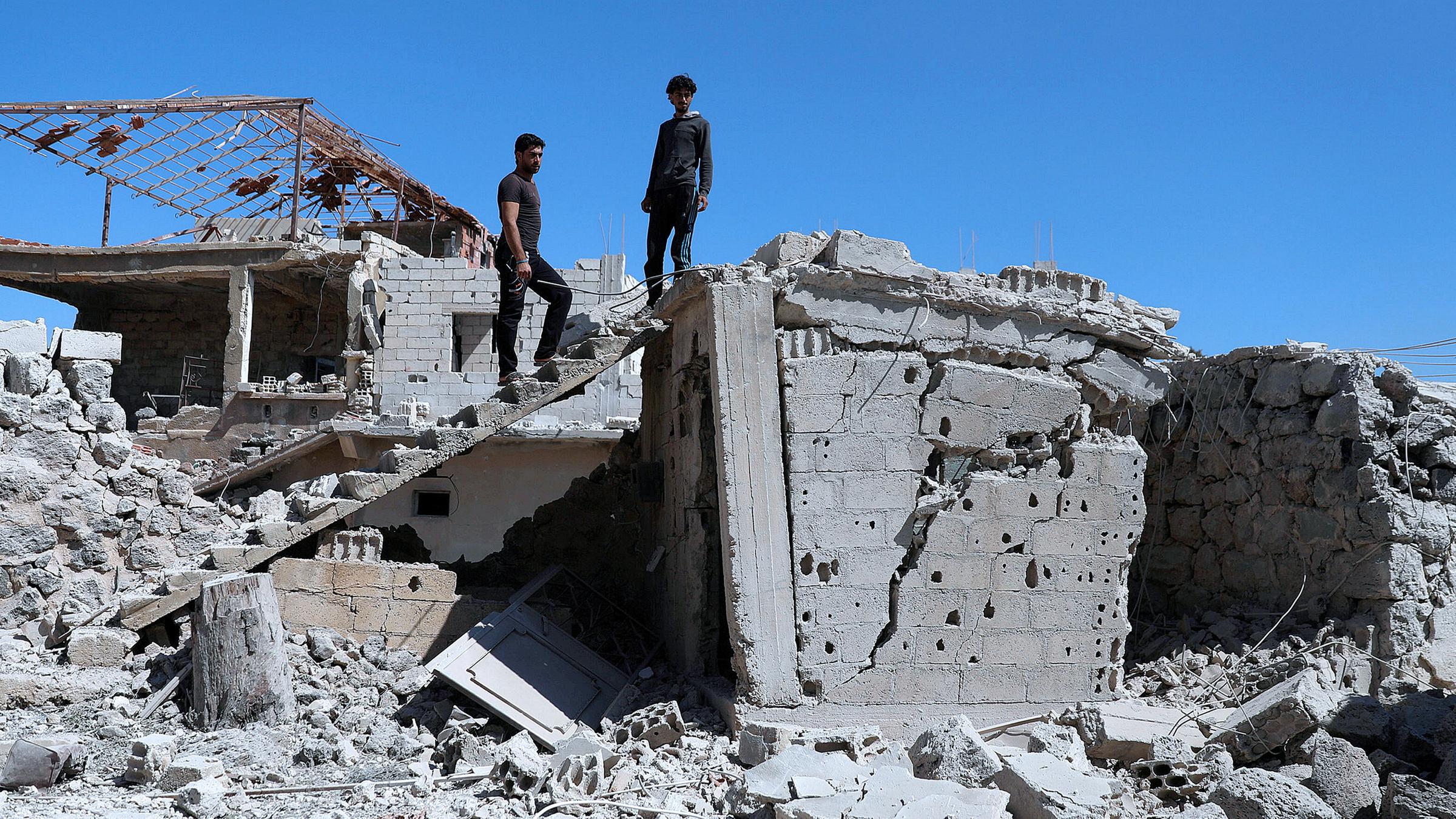 Archiv: Männer inspizieren ein zerstörtes Gebäude in Syrien