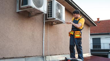 Techniker installiert Klimaanlage auf Dach.