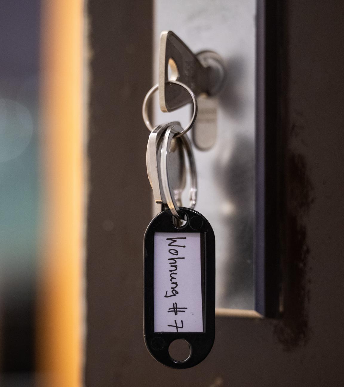  Ein Schlüssel mit der Aufschrift «Wohnung #7» hängt an einer Wohnungseingangstür. 