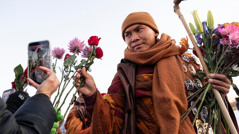 Der ehrwürdige Bhikkhu Pannakara nimmt eine Blume als Opfergabe entgegen, während er die Theravada-buddhistischen Mönche beim Friedensmarsch in Woodbridge, Virginia, USA