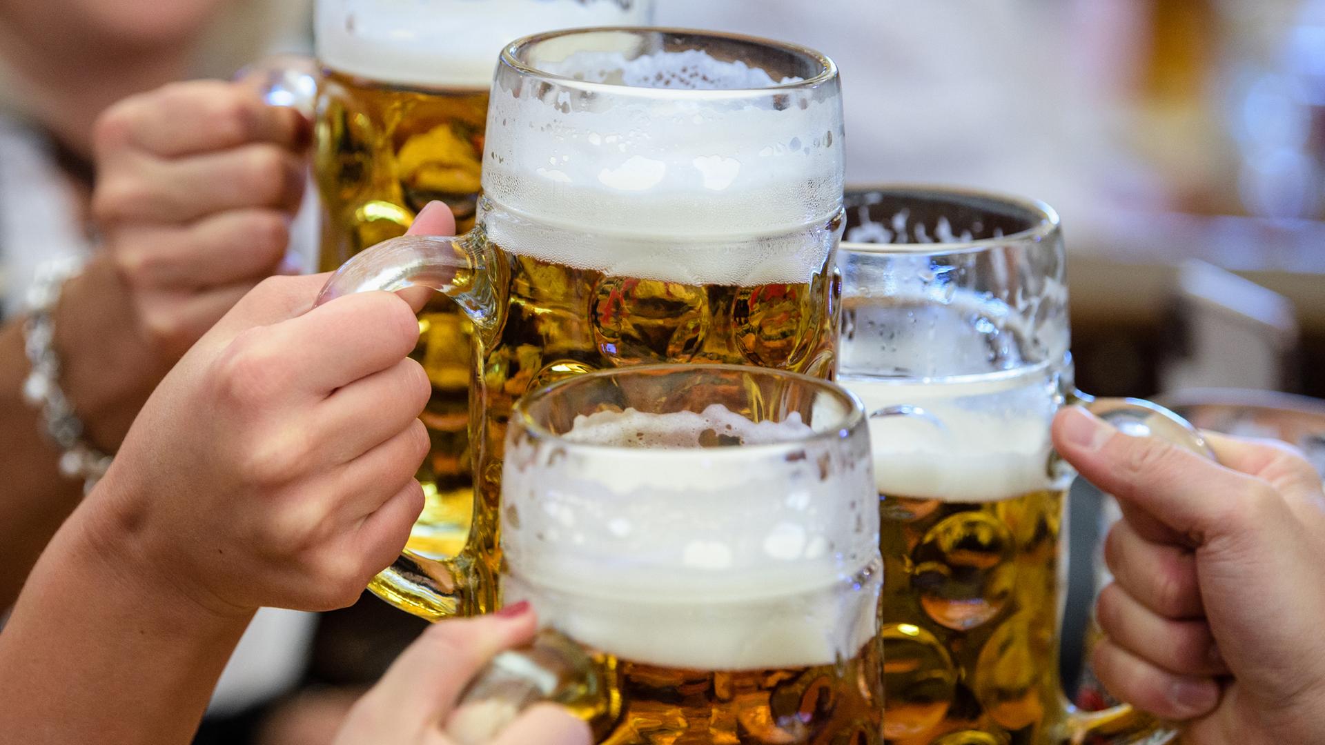 Besucher des Oktoberfestes stoßen mit Bier an. 