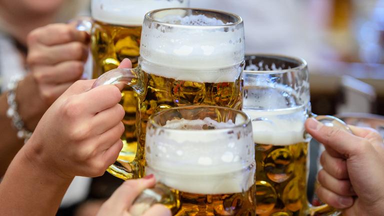 Besucher des Oktoberfestes stoßen mit Bier an. 