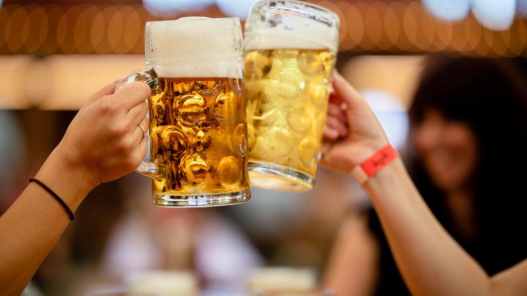 Besucher des 85. Stuttgarter Frühlingsfests stoßen in einem Festzelt mit zwei Mass Bier an. 