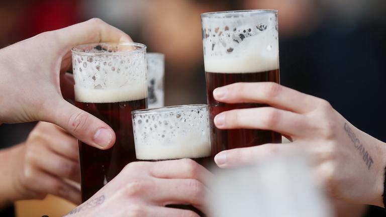 Düsseldorf: Gäste stoßen an einem Tisch im Außenbereich eines Lokals mit Altbier an.