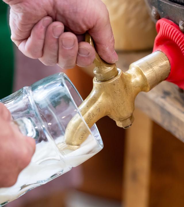 Hand an Zapfhahn eines Fasses. Bier läuft ins Glas.