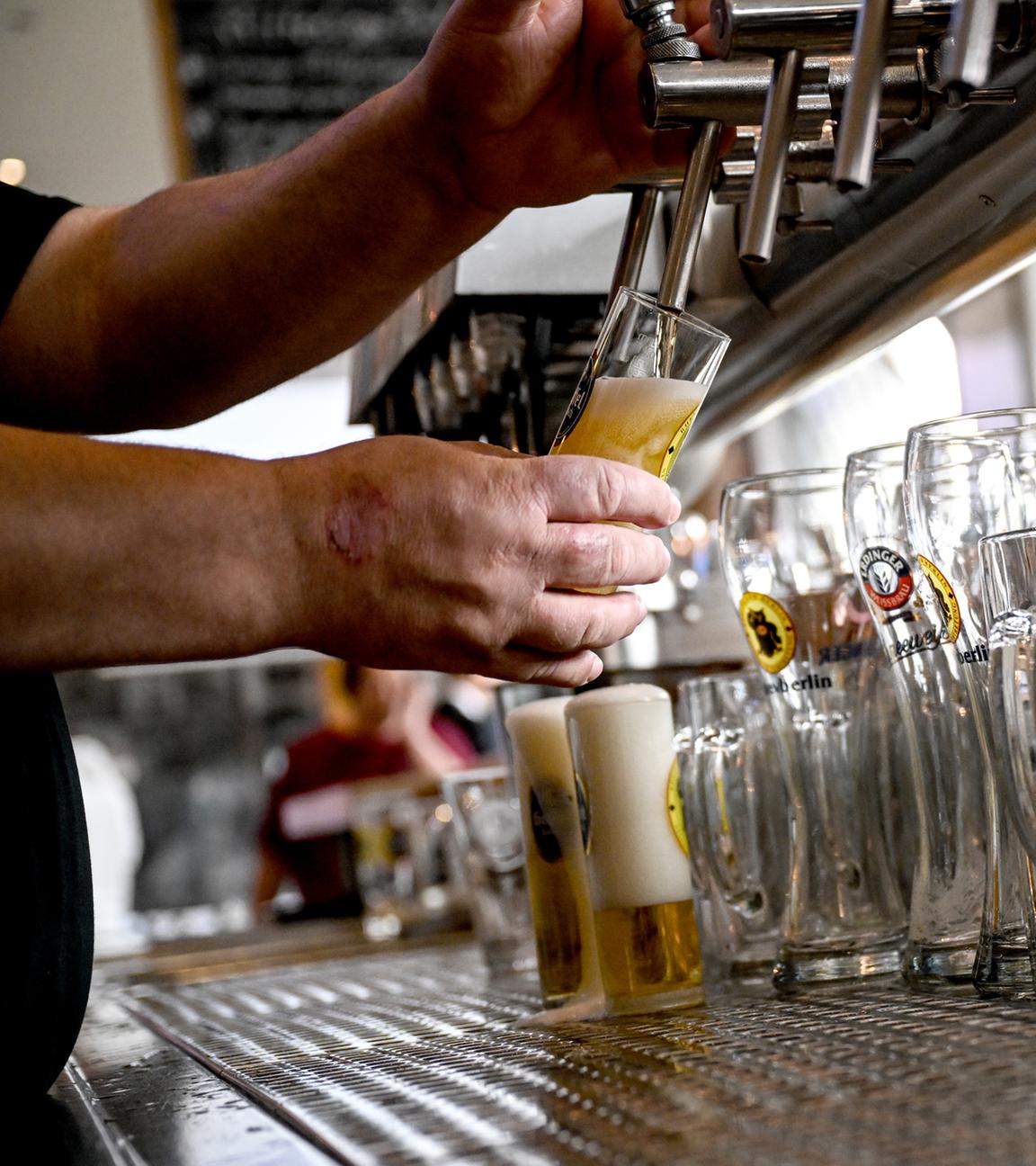 Ein Barkeeper zapft Bier.