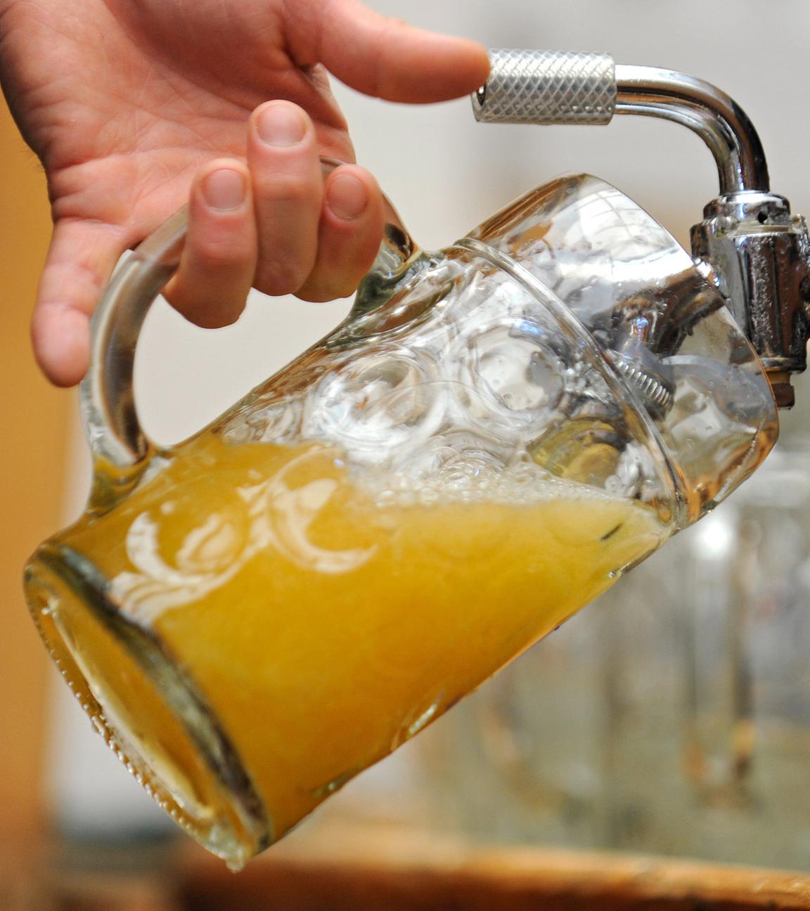 Symbolbild: Ein Mann zapft Bier aus einem Fass in ein Glas
