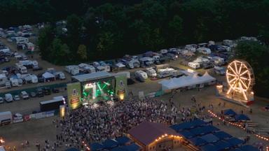 Eine Menschenmenge steht vor einer Bühne eines Festivals.