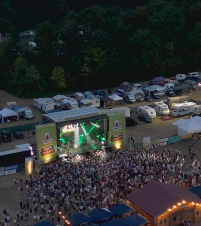 Eine Menschenmenge steht vor einer Bühne eines Festivals.
