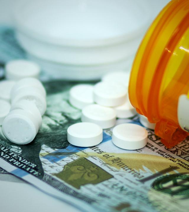 Nahaufnahme eines geöffneten Tablettendöschens, daneben liegen eine Tabletten auf.