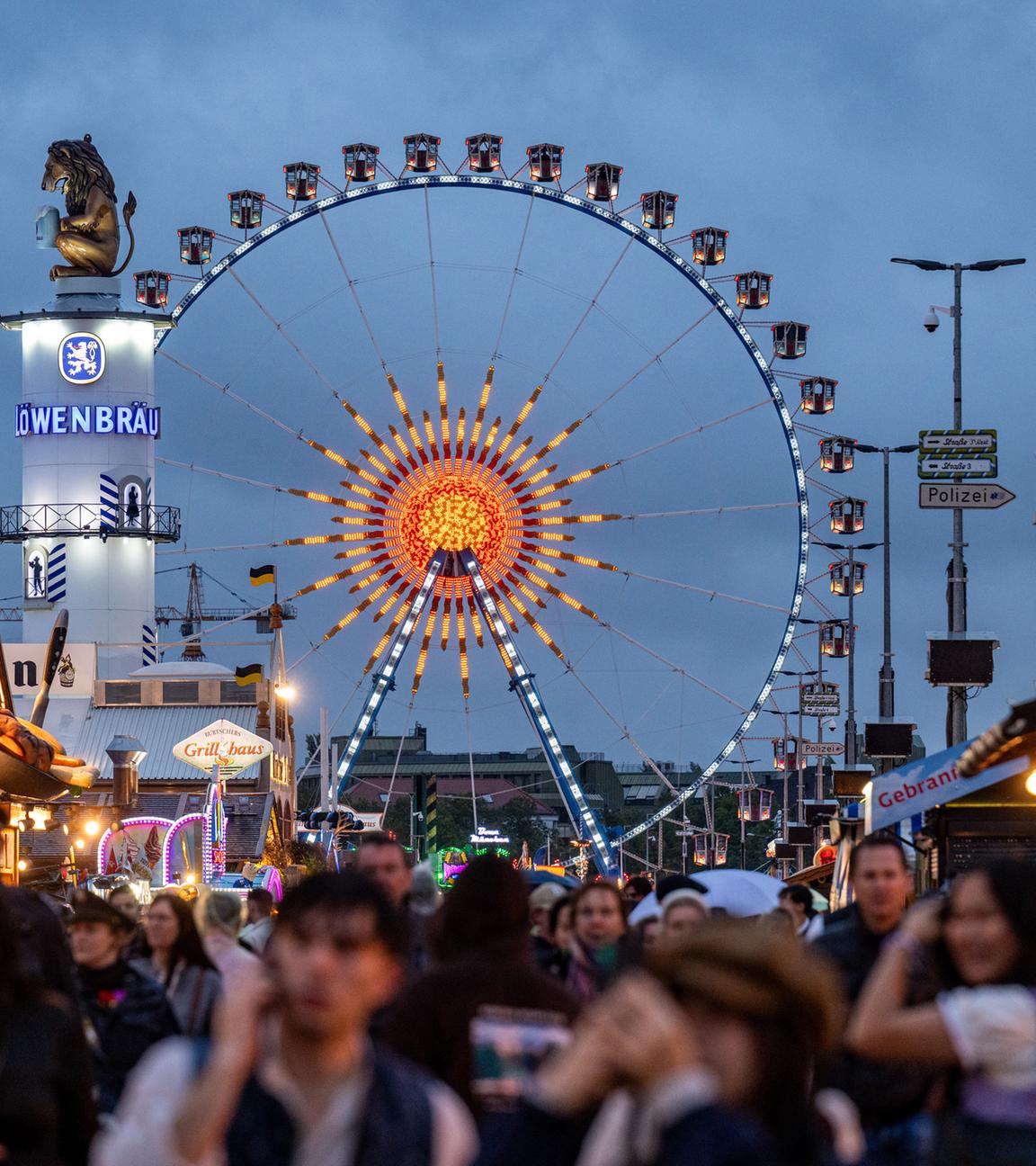 04.10.2025, Bayern, München: Besucher des Oktoberfestes gehen über das Festgelände.