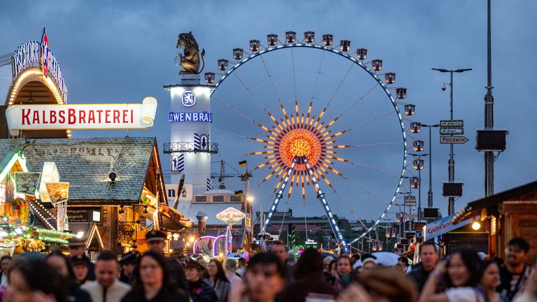 04.10.2025, Bayern, München: Besucher des Oktoberfestes gehen über das Festgelände.