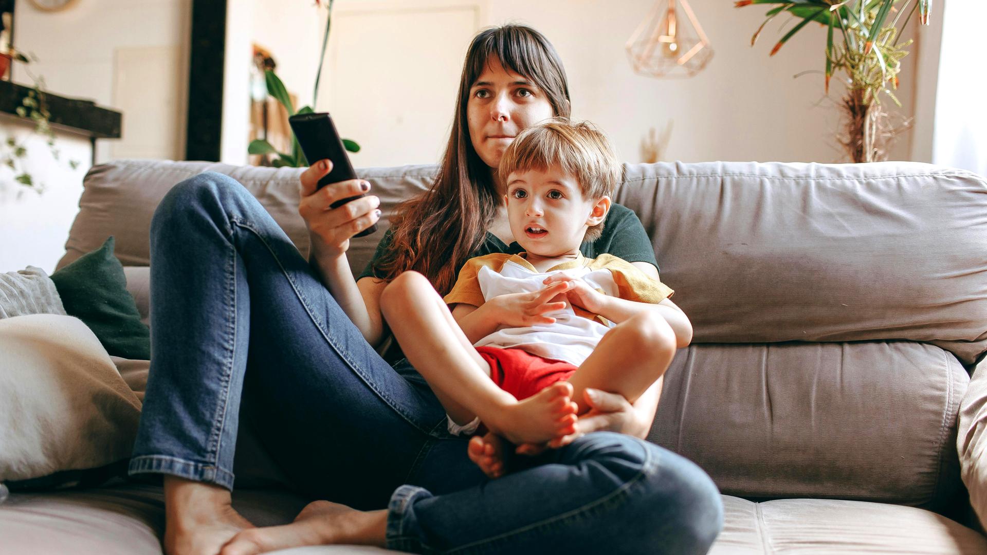 Typical Kinder- und Jeugendmedienschutz im ZDF: Mutter mit kleinem Kind im Schoss auf der Couch mit Fernbedienung