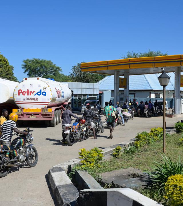 Vor einer Tankstelle in Malawi hat sich eine Schlage aus Motorrädern und LKW gebildet.