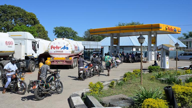 Vor einer Tankstelle in Malawi hat sich eine Schlage aus Motorrädern und LKW gebildet.