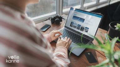 Eine Frau sitzt an ihrem Laptop. Sie ist auf einem Online-Reise-Portal unterwegs.