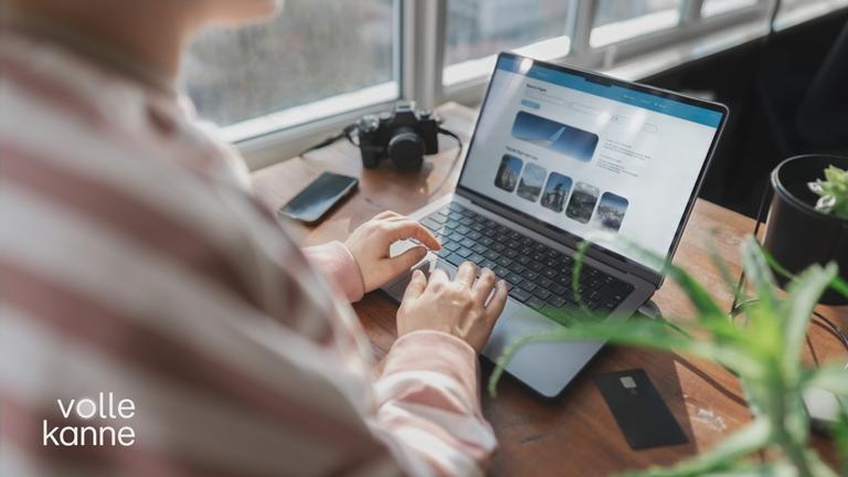 Eine Frau sitzt an ihrem Laptop. Sie ist auf einem Online-Reise-Portal unterwegs.