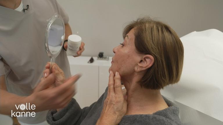 Eine Frau hält einen Handspiegel und betrachtet ihr Spiegelbild.