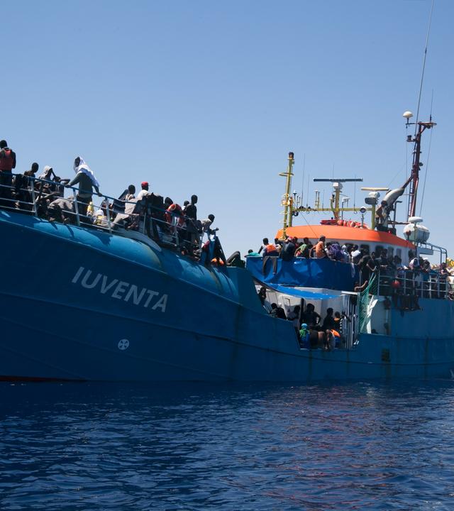 "I"Iuventa": Ein mit Menschen vollbesetztes Frachtschiff mit dem Namenszug „Iuventa“, von einem anderen Boot aus fotografiert, liegt im Mittelmeer.