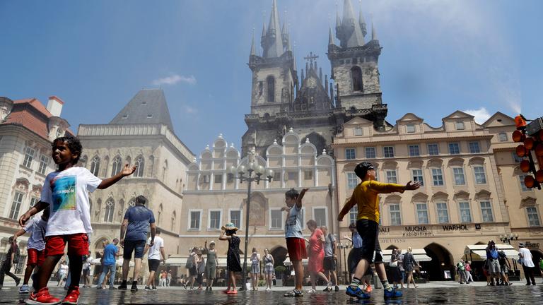 Die Menschen kühlen sich unter dem Strahl des Wassers ab, welches in die Luft gesprüht wird am 25.06.2019 in Prag ( Tschechische Republik  )
