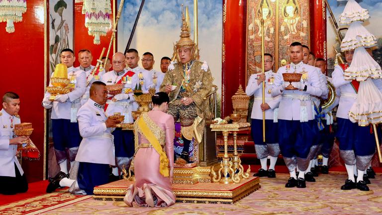 Maha Vajiralongkorn (m.) sitzt anlässlich seiner Krönung am 04. Mai 2019 auf dem Thron, während Königin Suthida vor ihm kniet.