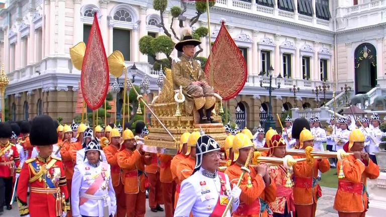 Rama X. wird auf einer königlichen Sänfte durch die Straßen von Bangkok getragen.