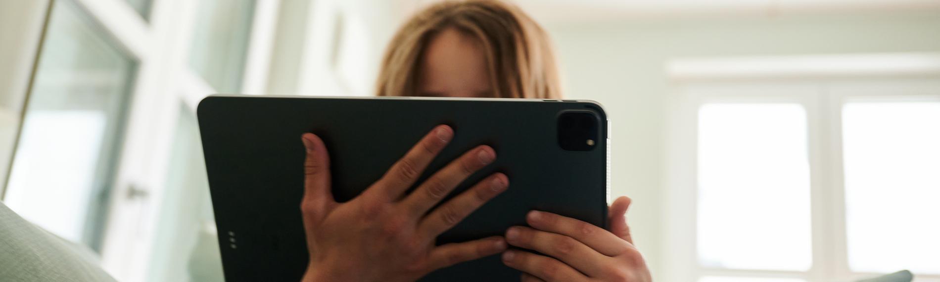 Mädchen sitzt mit Tablet auf dem Sofa