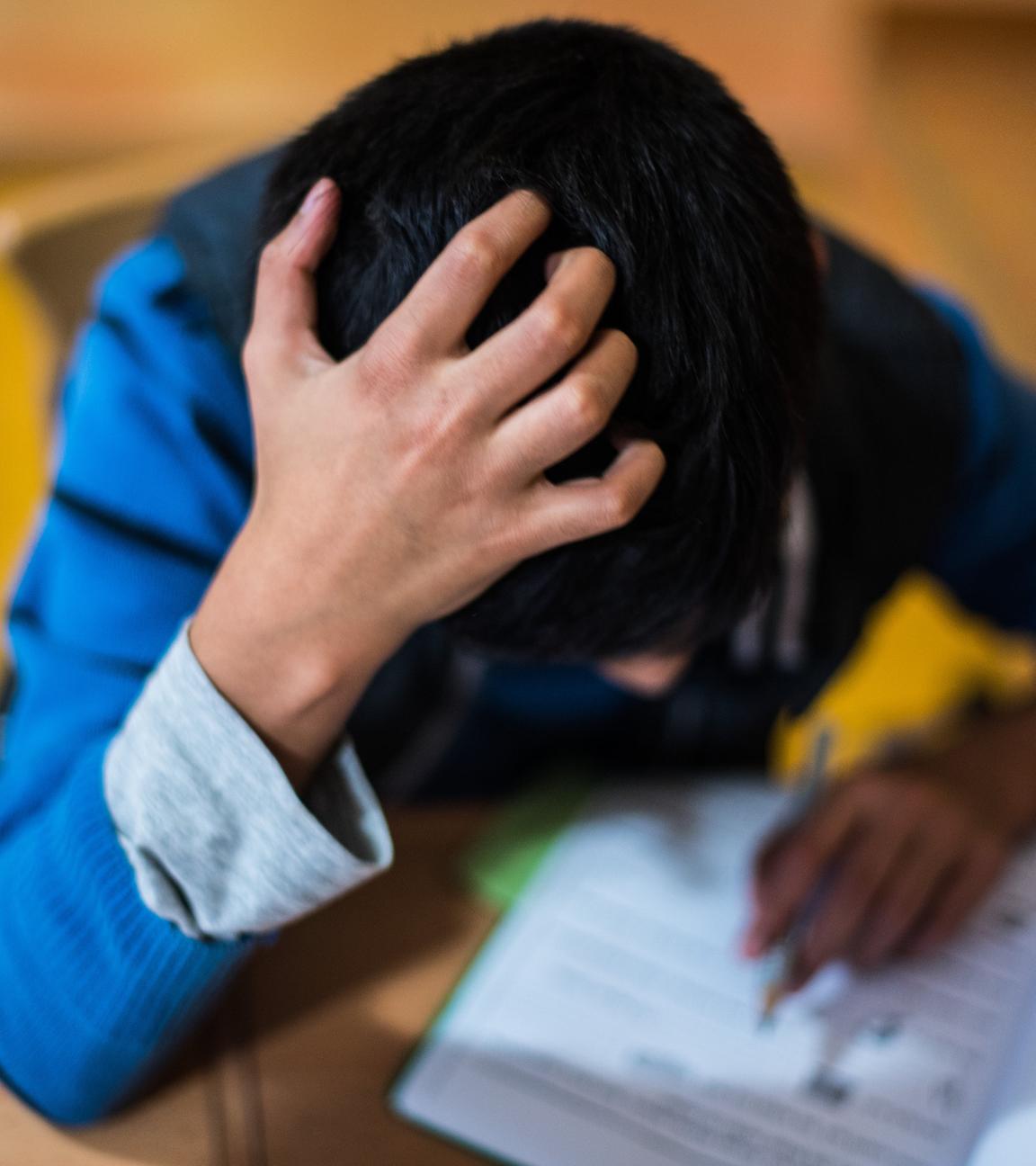 Ein Junge sitzt in der Hausaufgabenhilfe an seinen Schularbeiten.