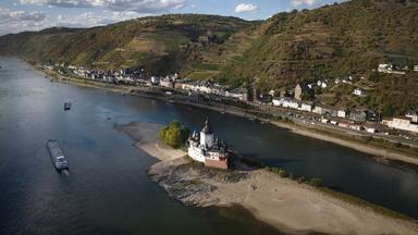 06.08.2026, Rheinland-Pfalz, Kaub: Ein Schiff fährt auf dem Rhein bei einem niedrigen Wasserstand an der Burg Pfalzgrafenstein vorbei. (Aufnahme mit Drohne)