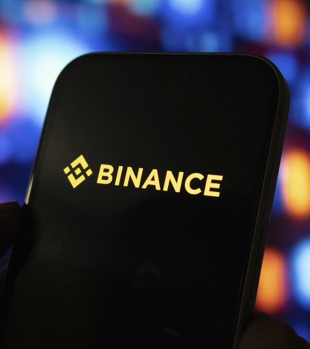 Eine Person hält Smartphone mit dem Logo der Krypobörse Binance auf dem Bildschirm.
