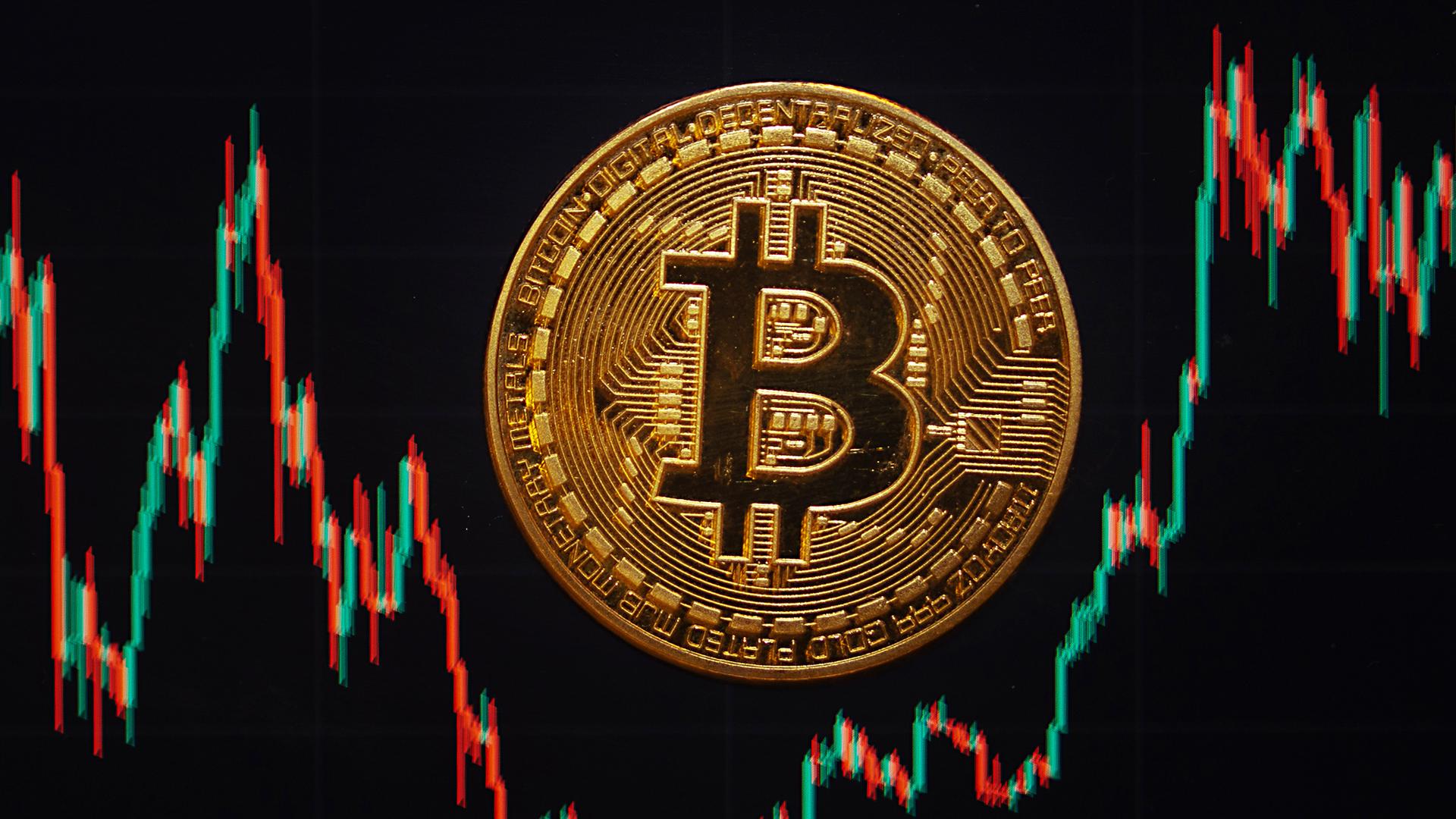 Symbolbild: Eine Bitcoin-Münze liegt auf einem Bildschirm, der den Bitcoin - US-Dollar Kurs zeigt. 