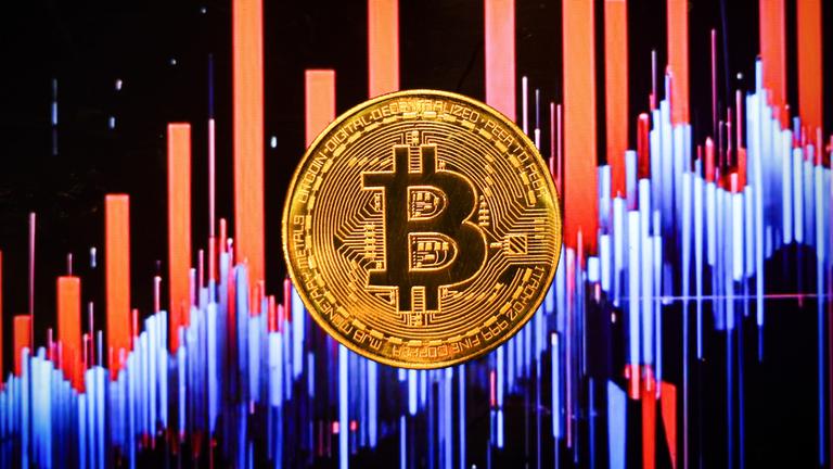 Bitcoin Münze mit angedeuteten Börsenkursbalken im Hintergrund. (Symbolbild)