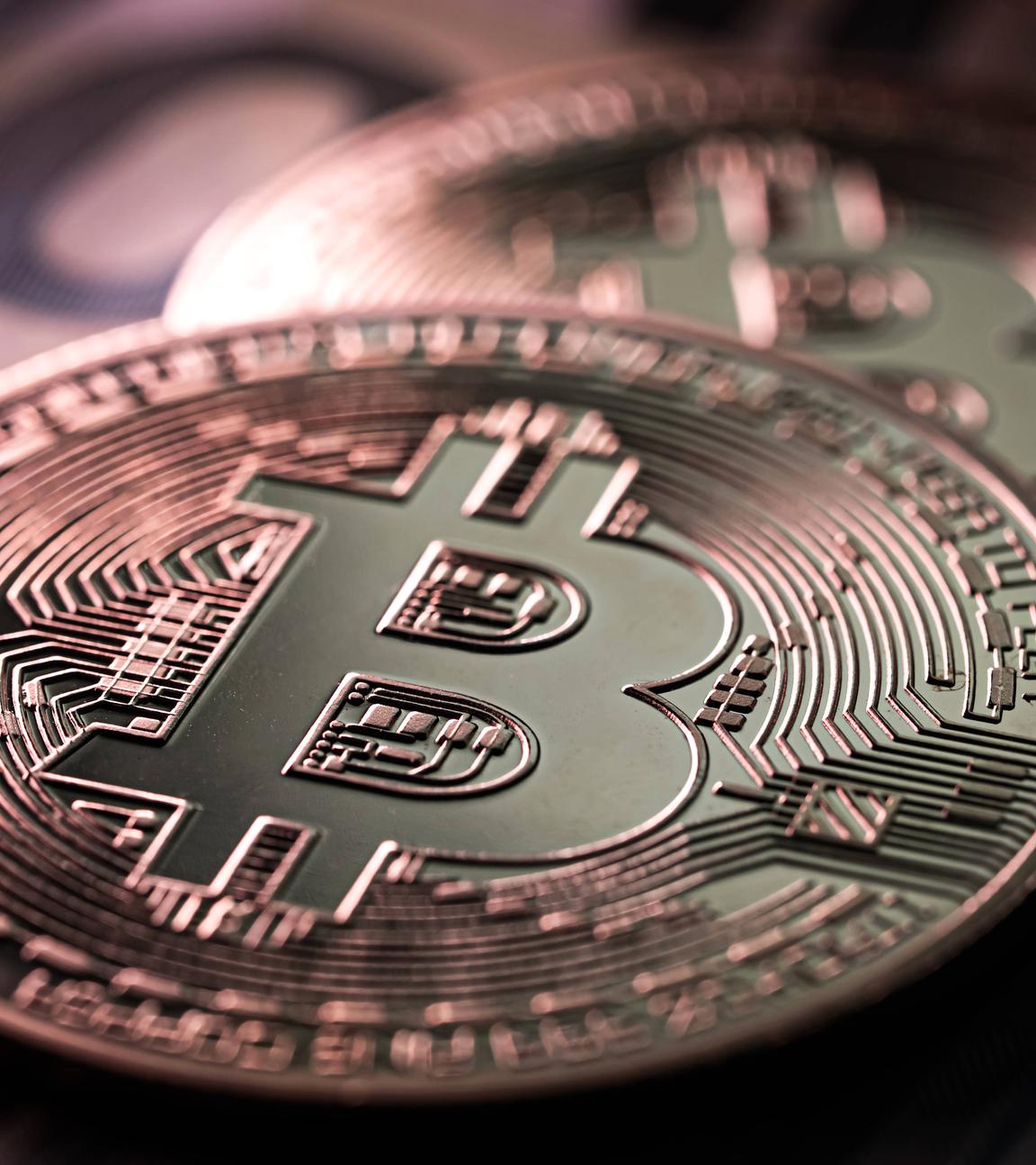 Nahaufnahme von zwei Bitcoin Münzen auf 100 Euro-Scheinen
