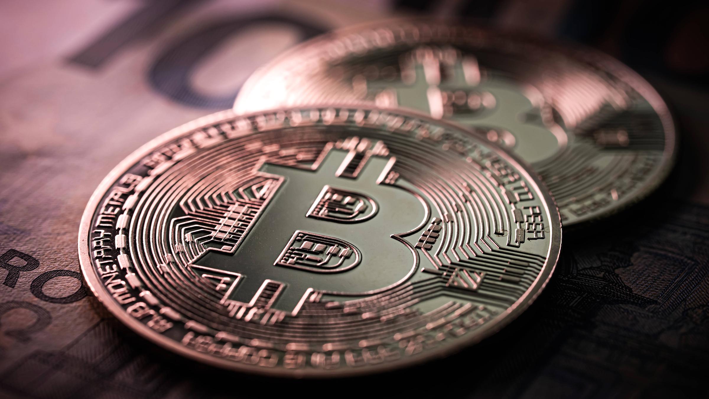 Nahaufnahme von zwei Bitcoin Münzen auf 100 Euro-Scheinen