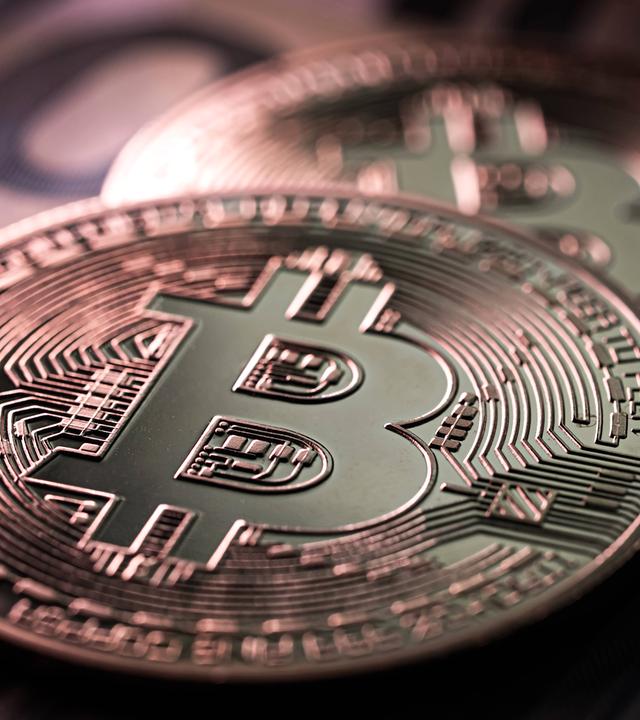 Nahaufnahme von zwei Bitcoin Münzen auf 100 Euro-Scheinen