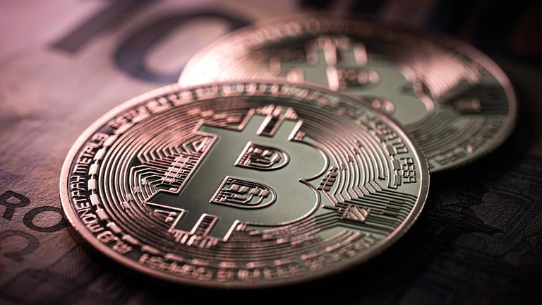 Nahaufnahme von zwei Bitcoin Münzen auf 100 Euro-Scheinen