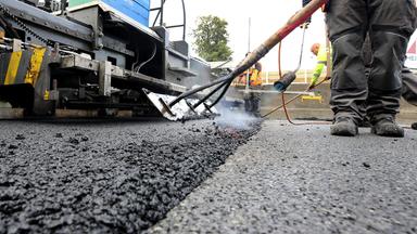 02.10.2020, Nordrhein-Westfalen, Mülheim: Arbeiter tragen auf einer Autobahn eine neue Asphaltdecke auf.