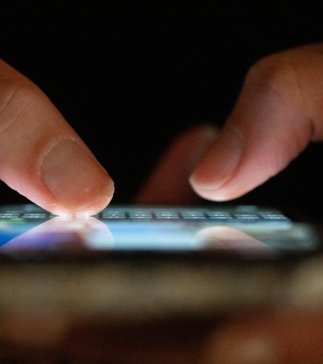 Eine Person tippt auf einem Smartphone.