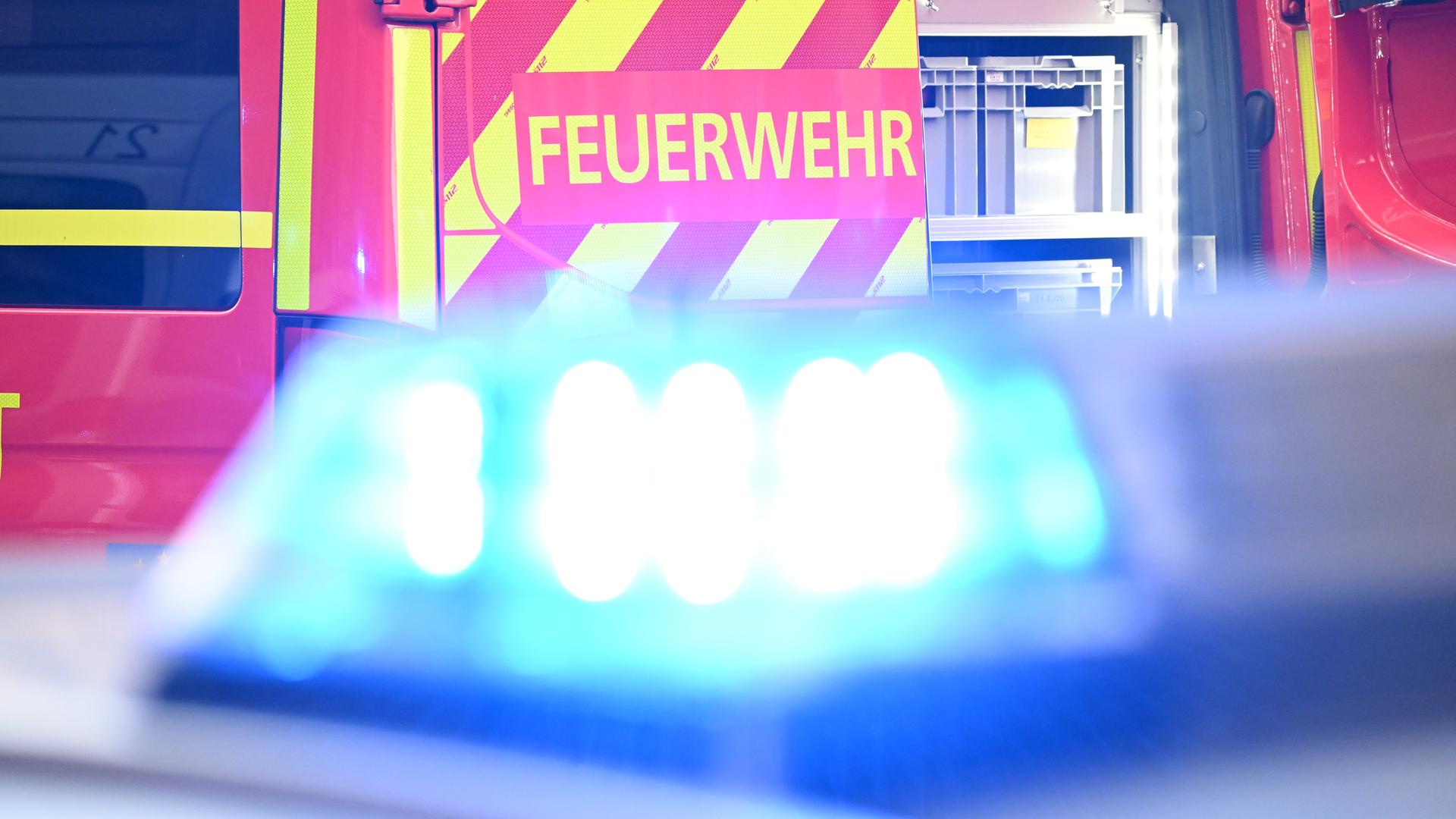 Blaulicht im Vordergrund, dahinter ein Feuerwehr-Fahrzeug mit der Aufschrift "Feuerwehr".
