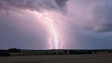 Ein Blitz zuckt bei einem Sommergewitter am abendlichen Himmel