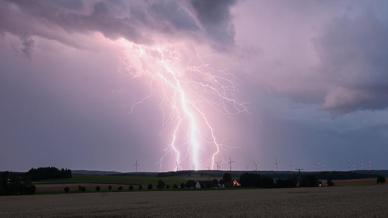 Ein Blitz zuckt bei einem Sommergewitter am abendlichen Himmel