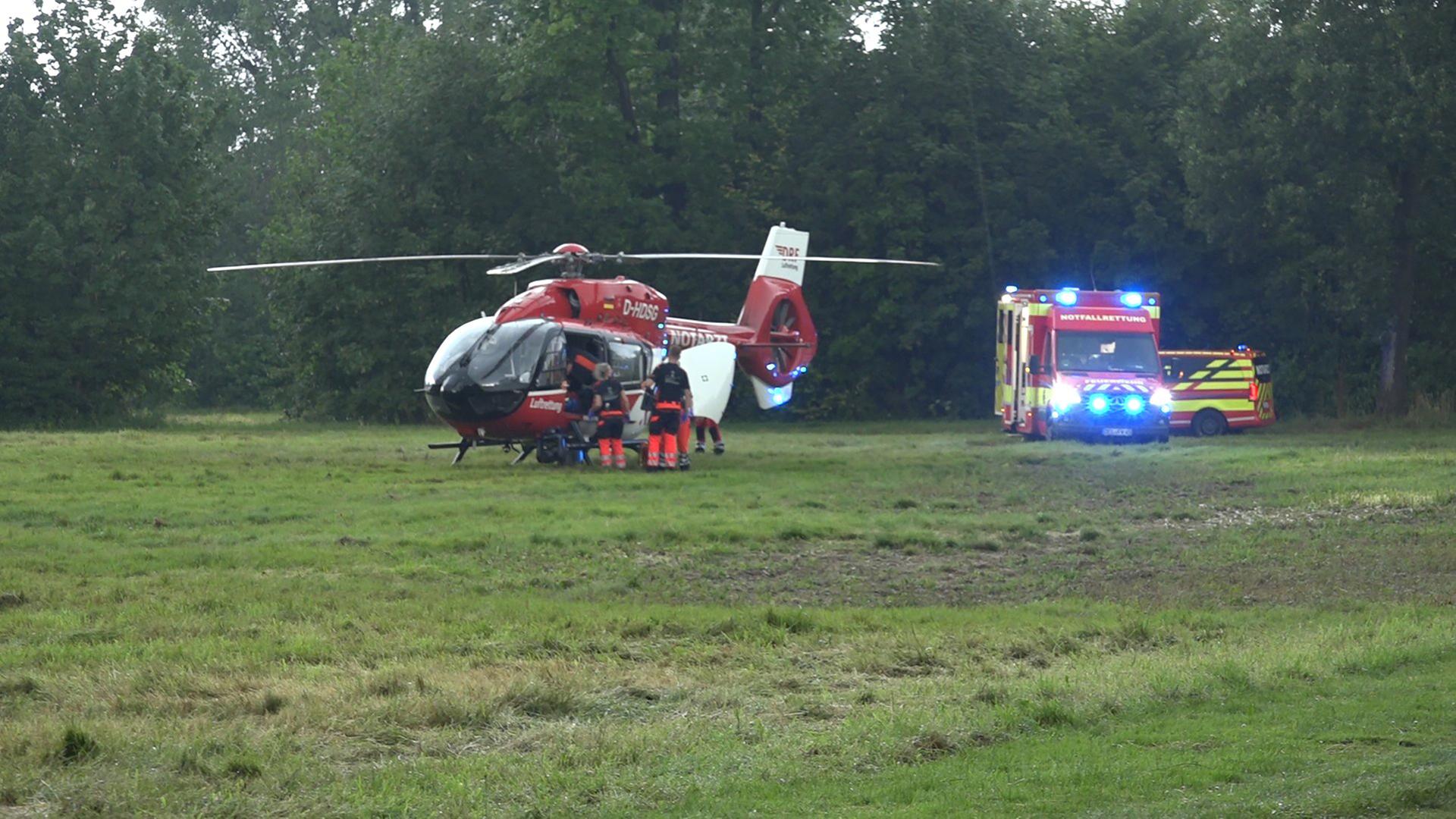Einsatzkräfte stehen bei einem Rettungshubschrauber und bereiten den Transport von Verletzten vor.
