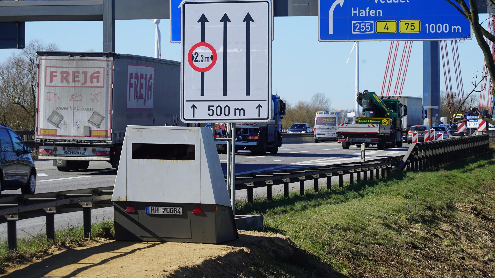 Ein mobiler Blitzer steht am Rand einer Autobahn. Es fahren Autos an ihm vorbei.