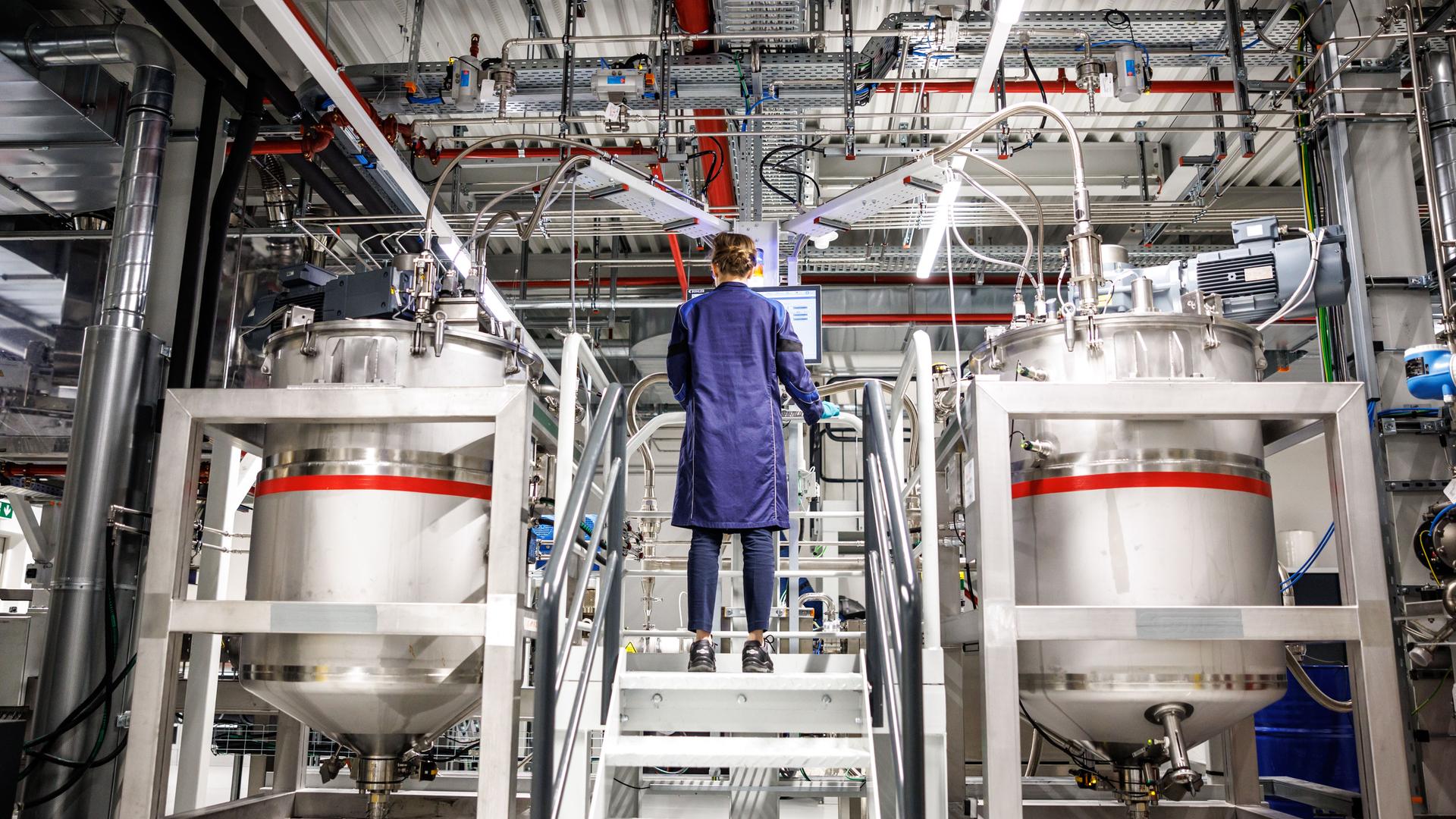 Bayern, Vaterstetten: Desiree Grießl, zuständig für die Technologie-Entwicklung Elektrode bei BMW, steht bei einem Presserundgang durch das BMW Kompetenzzentrum für Batteriezellfertigung Parsdorf (Cell Manufacturing Competence Centre, CMCC) in einer Werkshalle im Bereich "Dosieren und Mischen" zwischen zwei Mischbehältern, in denen die Batteriepaste ("Slurry") gemischt wird.