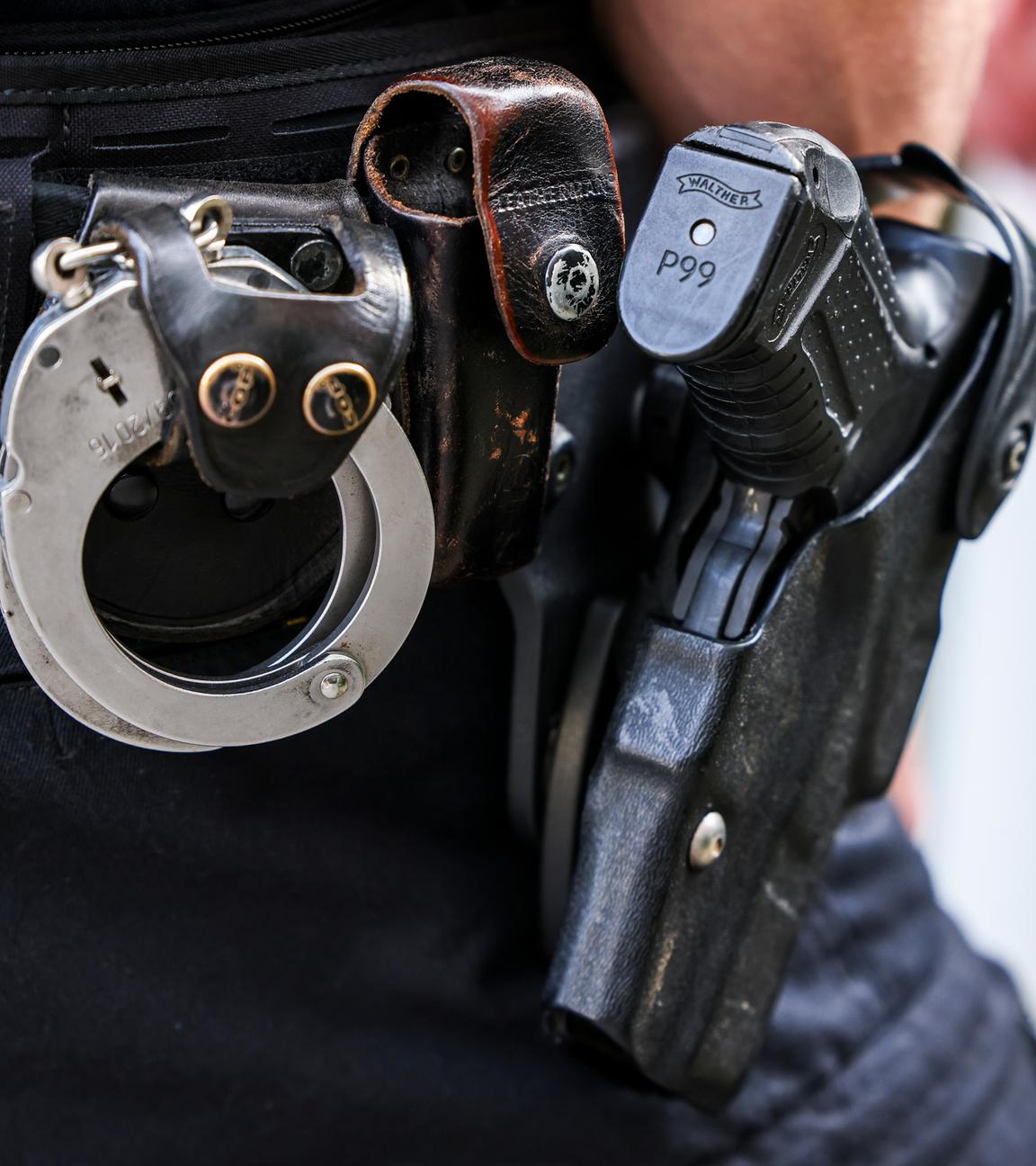 Ein Polizeibeamter trägt seine Dienstwaffe Walther P99 und Handschellen